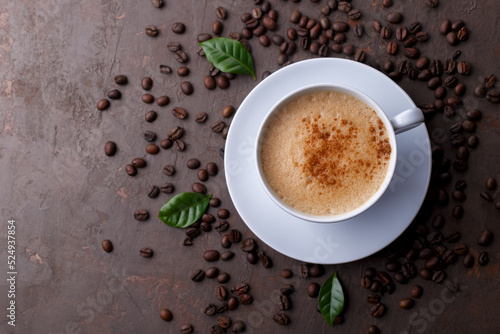 Cup of coffee cappuccino and coffee beans on the brown stone background