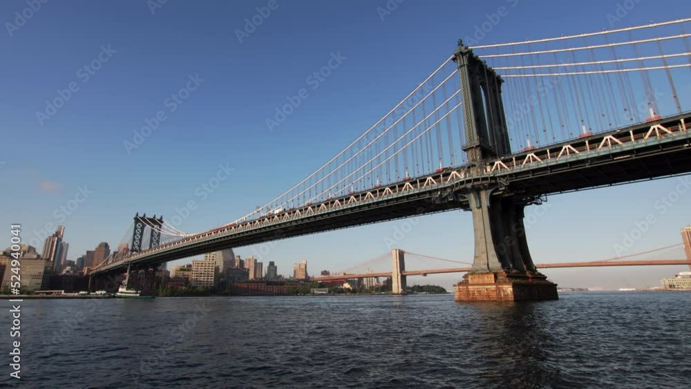 Panoramic view of the blue East river in summer, sailing barge, Brooklyn and Manhattan bridges across it. Skyscrapers on the background. NYC, USA Panoramic view of the blue East river in summer, sailing barge, Brooklyn and Manhattan bridges across it. Skyscrapers on the background. NYC, USA