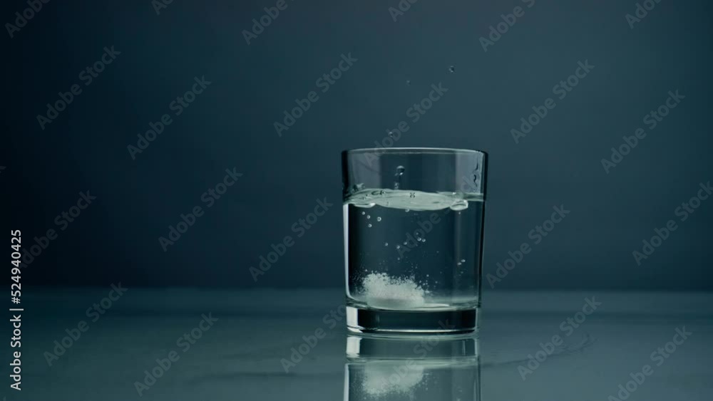 Effervescent tablet falling glass with water closeup. Dropped medicine bubbling Effervescent tablet falling glass with water closeup. Dropped medicine bubbling