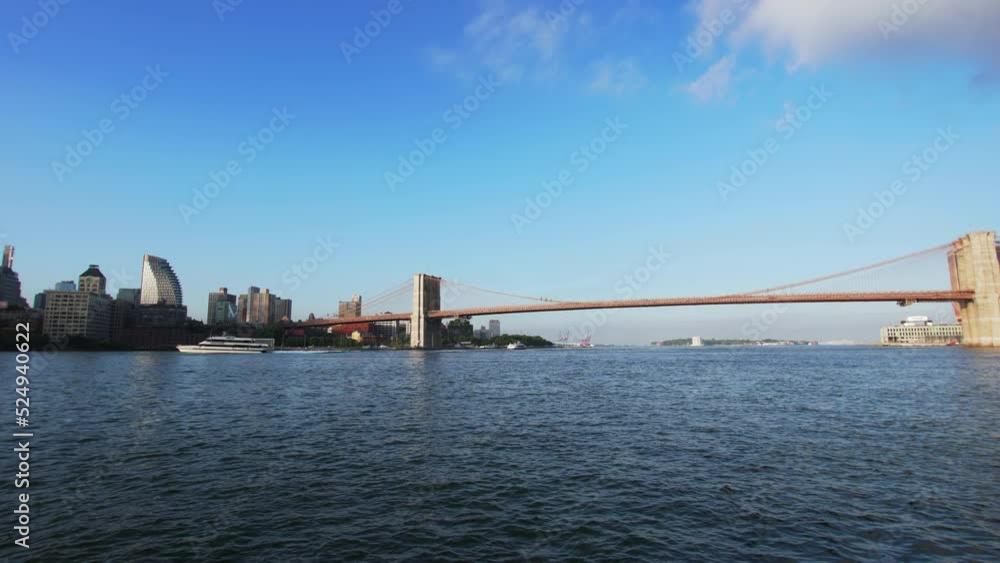Panoramic view of the blue East river in summer, sailing NYC ferry, Brooklyn and Manhattan bridges across it. Skyscrapers on the background. NYC, USA Panoramic view of the blue East river in summer, sailing NYC ferry, Brooklyn and Manhattan bridges across it. Skyscrapers on the background. NYC, USA