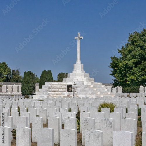 TYNE COT CEMETERY, BELGIUM - AUGUST `10, 2022: View across gravestones to the memorial cross at the cemetery