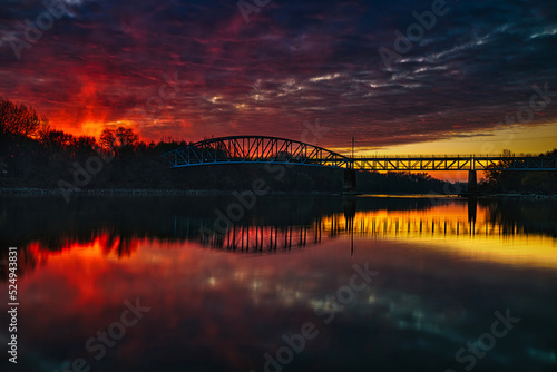 Sunset or sunrise like abstract hell coming over the bridge colored clouds and beautiful water reflection.