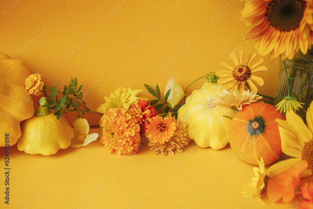 Stylish autumn composition. Colorful flowers, pumpkin, pattypan squash on yellow background. Creative modern autumnal still life. Seasons greeting card template with space for text. Hello Fall