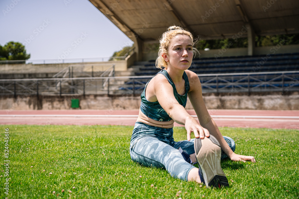 Fototapeta premium Sportswoman warming up on lawn on stadium