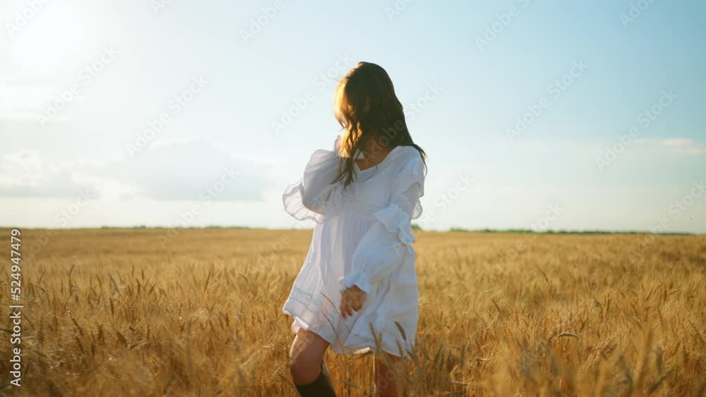 happy young woman in white dress with string bag with bread is whirling in rye field in summer sunny day happy young woman in white dress with string bag with bread is whirling in rye field in summer sunny day