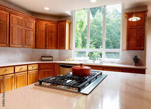 kitchen stovetop with stone counters, cherry cabinets and a large window with daylight coming in