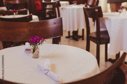 Mesa de salón comedor estilo Art Deco. Florero diminuto sobre mantel blanco.