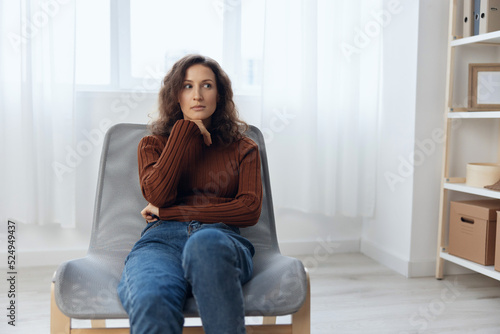 Thoughtful focused frustrated curly pretty woman cross hands lost in sad thoughts about irreparable mistake decision about divorce sit in chair at home looks aside. Depression Heavy thoughts concept
