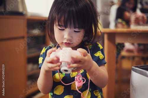 おもちゃのカメラで遊ぶ2歳の女の子