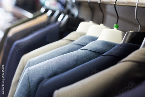 Assortment of suit jackets on hanger racks in menswear clothing store for selling