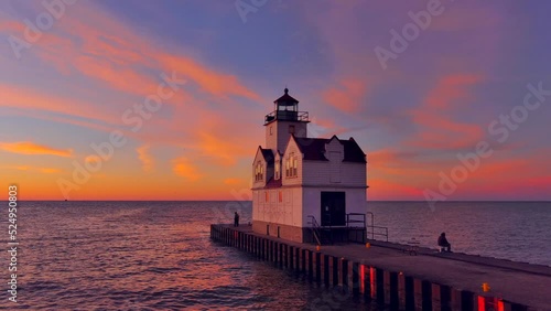 Incredible, colorful sunrise sky over lighthouse, silhouetted people fishing.
 photo