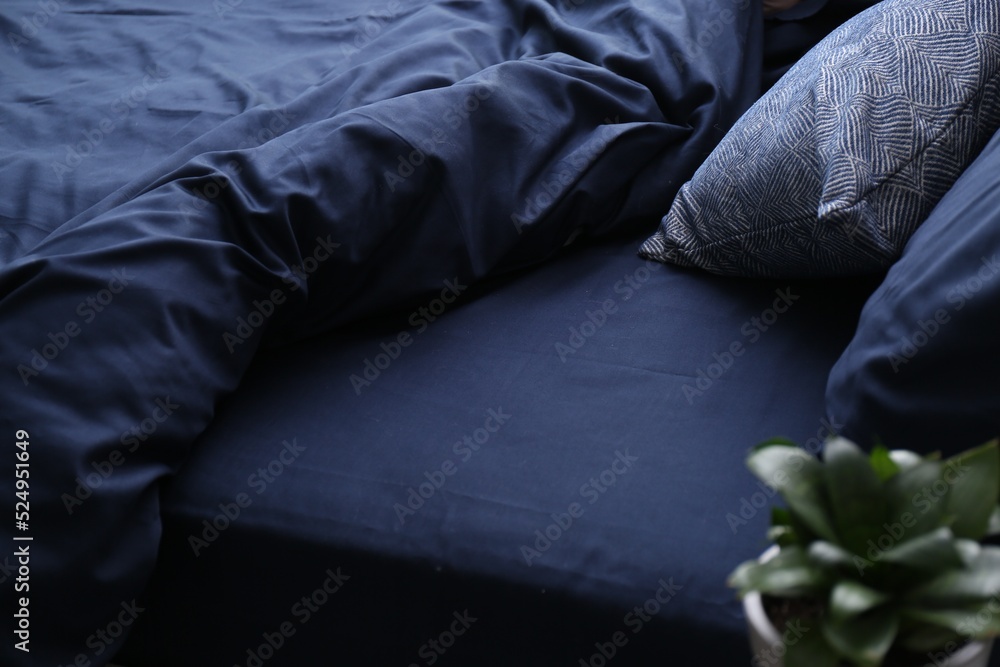Bed with stylish silky linens in room Bed with stylish silky linens in room