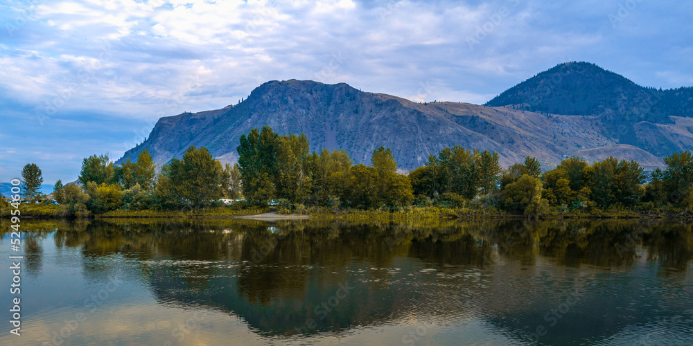 Tranquil Thompson River and mountain reflections at Pioneer Park in Kamloops, British Columbia, Canada. Autumn leaves