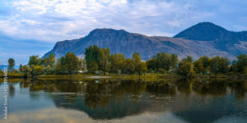 Tranquil Thompson River and mountain reflections at Pioneer Park in Kamloops, British Columbia, Canada. Autumn leaves