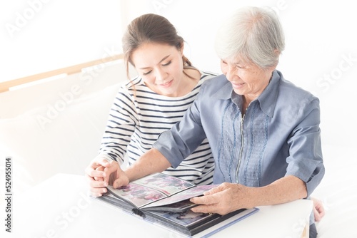 young asian female and her mother looking photo book, family time, hand in hand