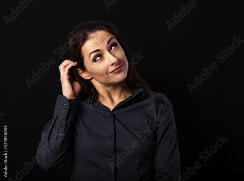 Beautiful thinking serious business woman scratching her head in blue shirt on black background with empty copy space for text. Closeup