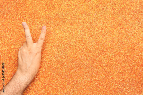 hand in orange glove peace victory glossy background 