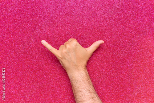 gesture with man's right hand of relaxation shaka or shaka relaxed and drink in man's hand on glow pink background