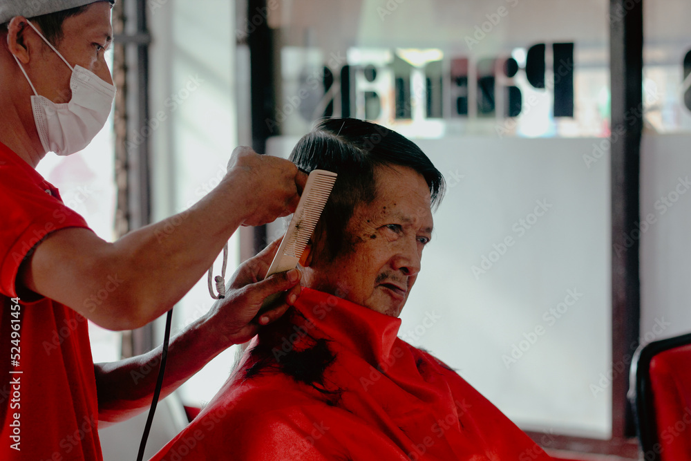 The barber man is cutting the old man's hair The barber man is cutting the old man's hair