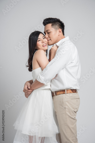 Happy young Asian couple in love embracing and kissing on white background