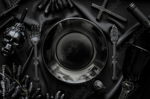 Halloween dinner party concept with black accessories, a bottle and glass of wine and grape fruits put on cloth background.