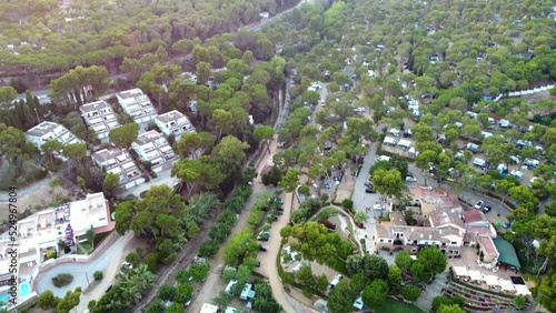 Famous campsite in forest on the beachFantastic aerial view flight tilt down drone footage at sunset golden houre evening in spain aro beach summer 2022. photo