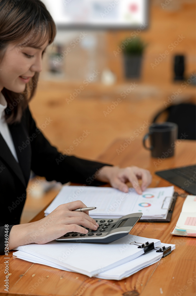 Female accountant calculating graph chart financial and marketing at office. Female accountant calculating graph chart financial and marketing at office.