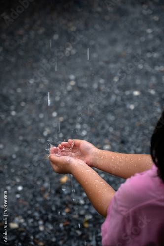 Hand of child playing and catching raindrops.