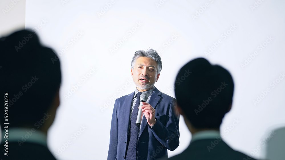 Fototapeta premium 登壇する男性と聴衆 セミナー プレゼンテーション
