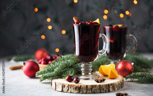  Glasses of mulled wine with cranberries and a cinnamon stick on a Christmas background with bokeh.