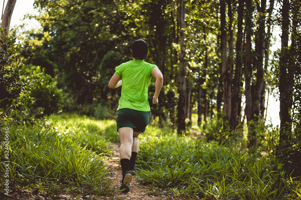Woman trail runner running at sunrise tropical forest mountain peak Woman trail runner running at sunrise tropical forest mountain peak
