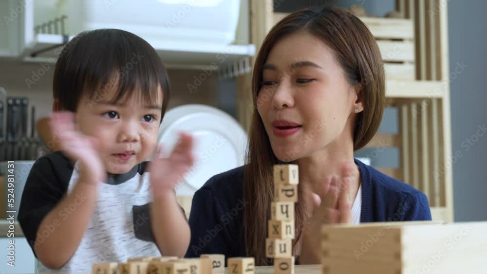 Asian young mother is teaching her little son to play with toys and clap for her son in the kitchen at house. Asian young mother is teaching her little son to play with toys and clap for her son in the kitchen at house.