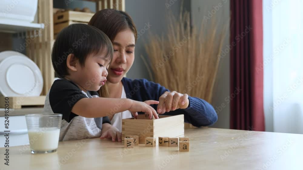 Asian young mother playing with toys with her lovely son in the kitchen at house.