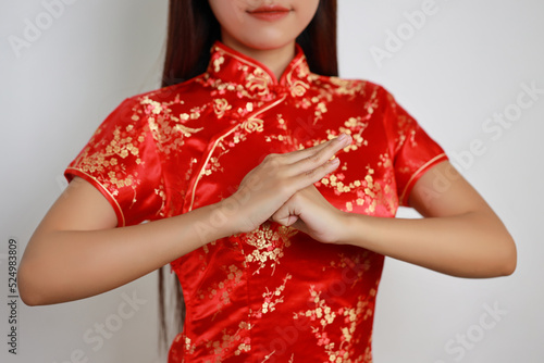Close up short of young Asian woman hands in red Chinese dress traditional cheongsam qipao with gesture of congratulation with white screen isolated (Chinese new year concept) photo