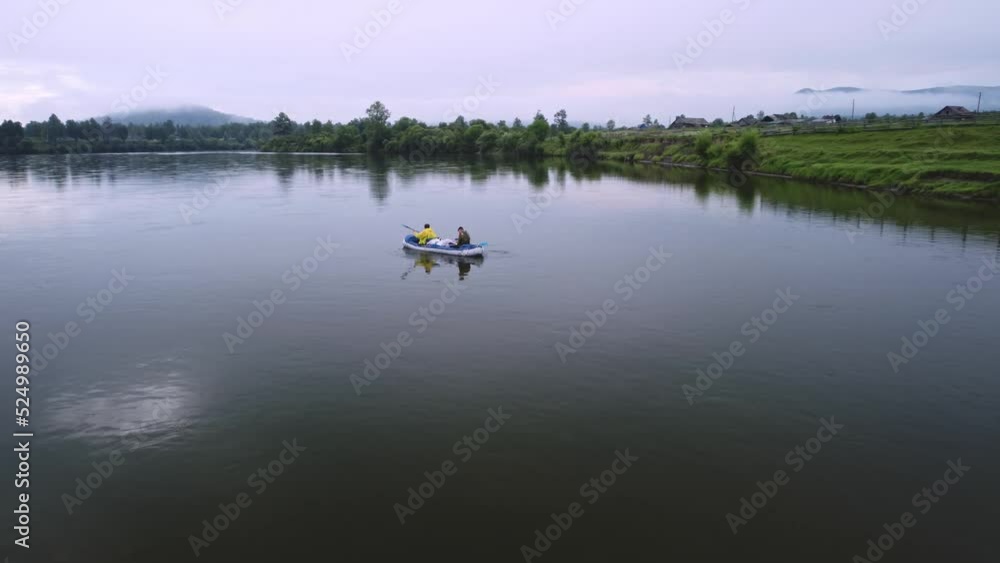 Two men are rafting on a calm river on an inflatable kayak on the Siberian river in summer. Active weekend in the wild Two men are rafting on a calm river on an inflatable kayak on the Siberian river in summer. Active weekend in the wild