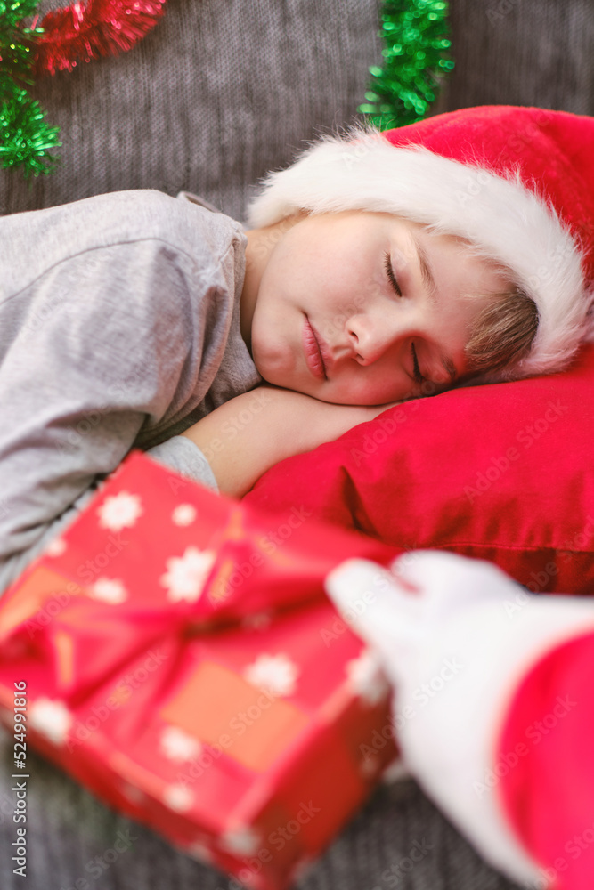 Santa Claus lays a Christmas gift to a sleeping child close-up. Santa Claus lays a Christmas gift to a sleeping child close-up.
