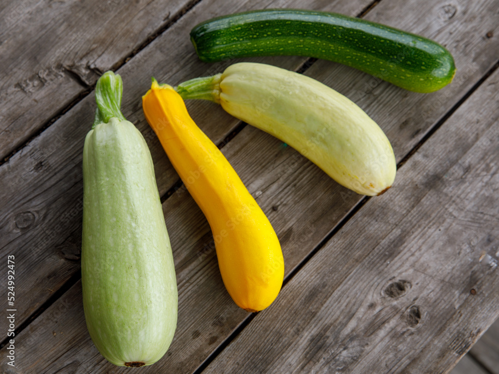 fresh mixed yellow, white, stripped and green zucchini's on a wooden background. Top view flat lay, close up fresh mixed yellow, white, stripped and green zucchini's on a wooden background. Top view flat lay, close up