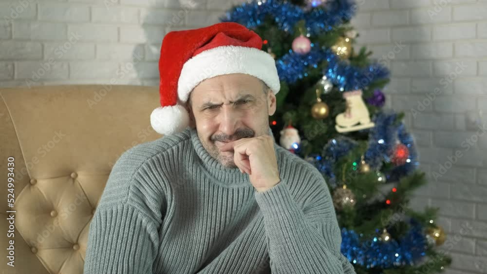 Pessimistic thoughts at Christmas. A man with pessimistic thoughts sits in loneliness by Christmas tree. Pessimistic thoughts at Christmas. A man with pessimistic thoughts sits in loneliness by Christmas tree.