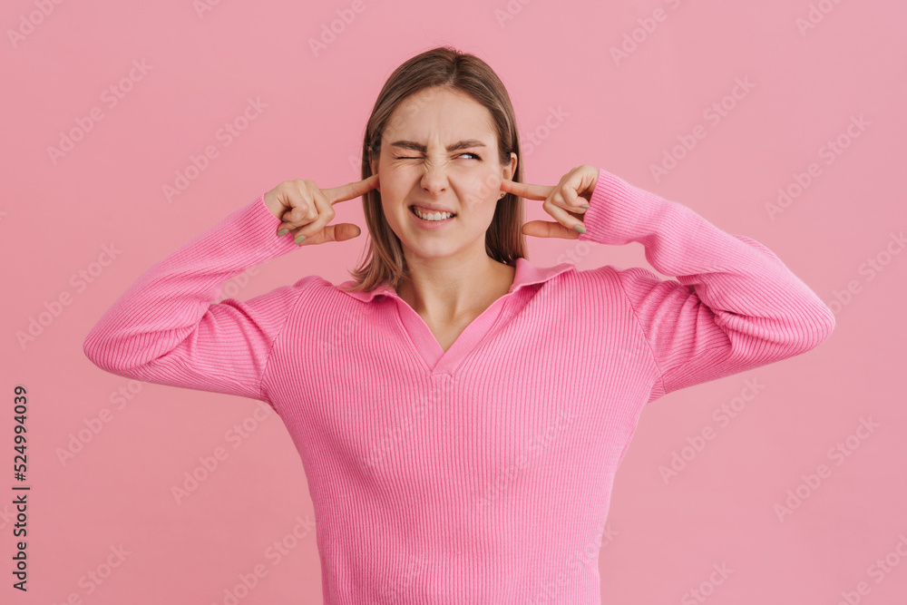 Young beautiful white woman wearing shirt frowning and plugging ears Young beautiful white woman wearing shirt frowning and plugging ears