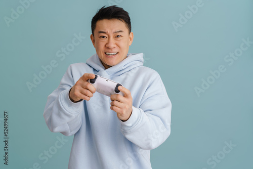 Принти на полотні Asian angry man grimacing while playing video game with joystick
