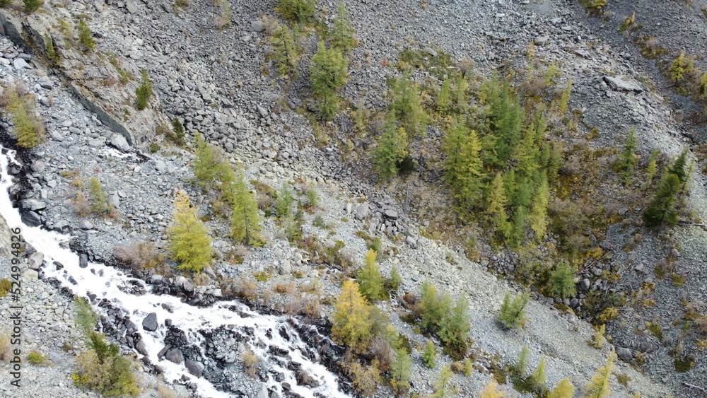 Mountain flowing stream and waterfall in the forest. Picturesque aerial drone landscape view. Altai mountains, Russia