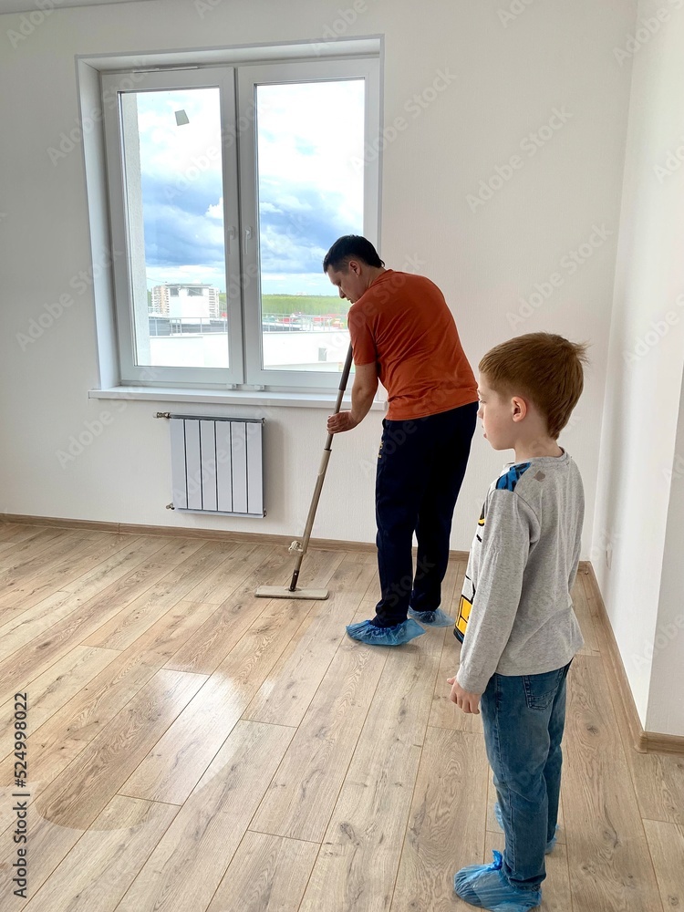 Father and son washing the floor in a new apartment, life style, the concept of moving to a new house, cleaning the apartment Father and son washing the floor in a new apartment, life style, the concept of moving to a new house, cleaning the apartment