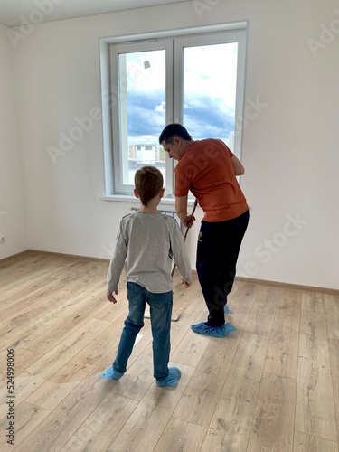 Father and son washing the floor in a new apartment, life style, the concept of moving to a new house, cleaning the apartment, rear view