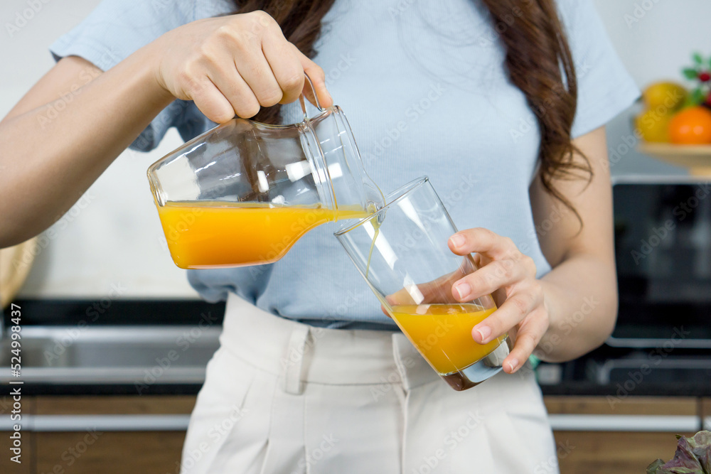 Closeup female hand pour mixed fruit and veggie smoothie from Jar into glass. Closeup female hand pour mixed fruit and veggie smoothie from Jar into glass.