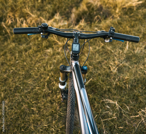 Bike handlebars. First-person view of mountain bicycle on the forest path. Riding a bike in a beautiful summer sunset nature landscape.