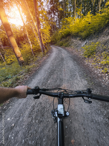 Close up of bicycle handle bar. First-person view of bicycle riding. Man riding a bike. Holding bike handlebar with one hand. Summertime outdoor leisure sport activity.
