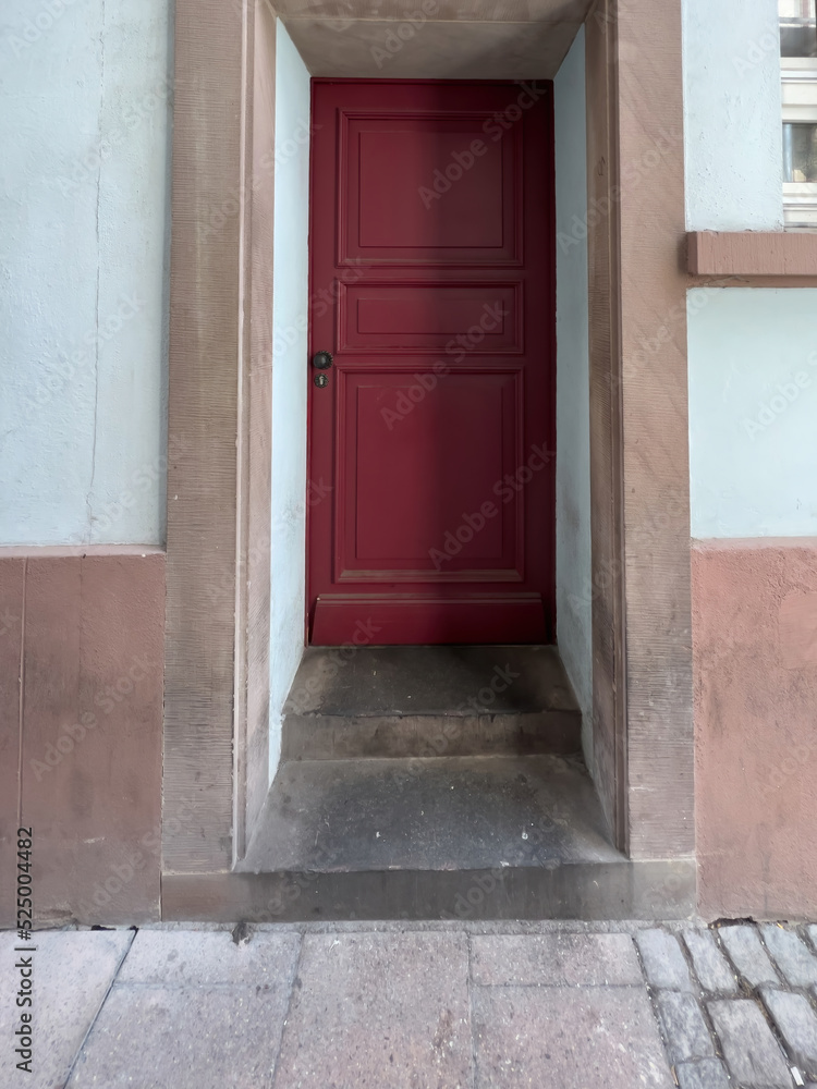 View from the street at welcoming cleanly painted red door with black steel door handle