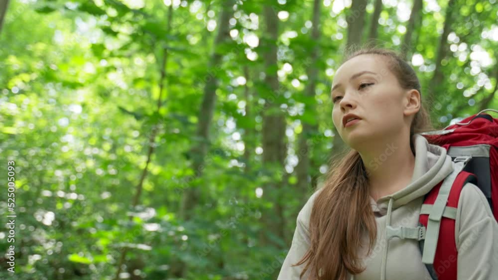 Couple of young tourists hikes in dense forest. Young girlfriend stops and asks for help. Brown-haired lady looks with tired and exhausted expression Couple of young tourists hikes in dense forest. Young girlfriend stops and asks for help. Brown-haired lady looks with tired and exhausted expression