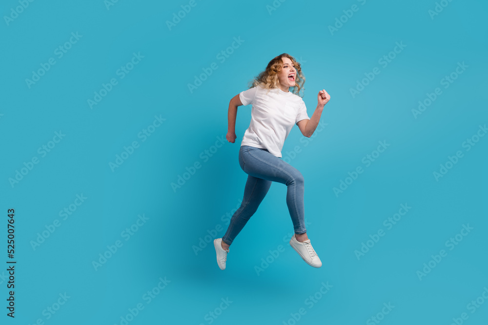 Full size profile side photo of young beautiful happy positive smiling girl running isolated on blue color background