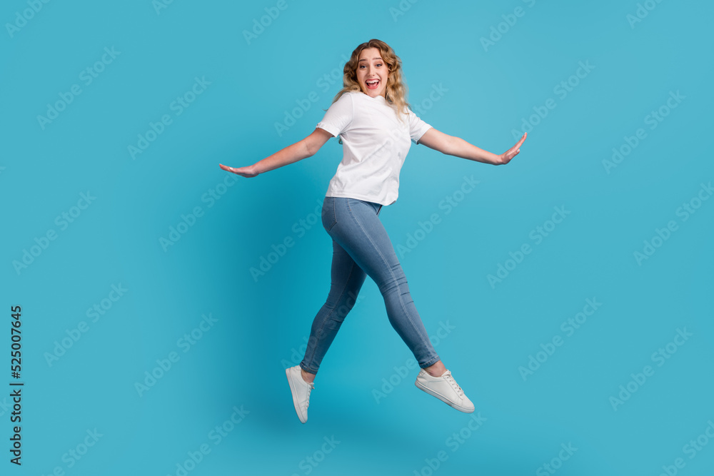 Full size profile side photo of young beautiful happy smiling girl running isolated on blue color background